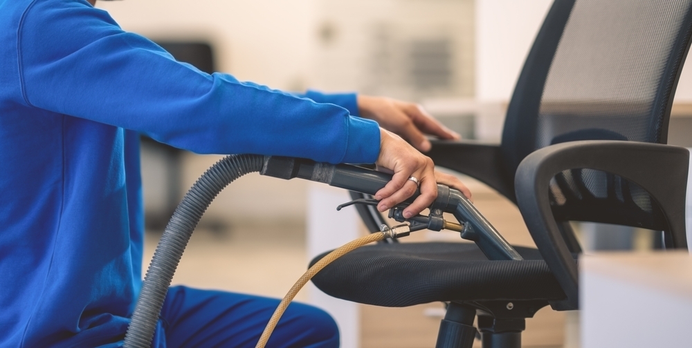 Rengøringsmedarbejder som støvsuger en kontor stol til erhvervsrengøring i Slagelse.